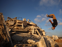 A Palestinian youth is practicing parkour at the ruins of a building destroyed in recent Israeli air strikes, in Zawayda in the central Gaza...