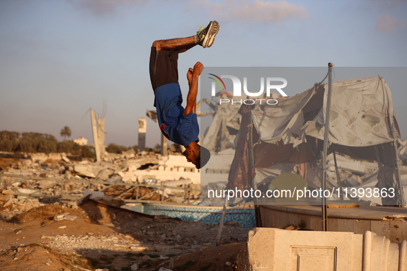 A Palestinian youth is practicing parkour at the ruins of a building destroyed in recent Israeli air strikes, in Zawayda in the central Gaza...