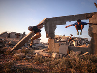 Palestinian youths are playing parkour at the ruins of a building destroyed in recent Israeli air strikes, in Zawayda, in the central Gaza S...