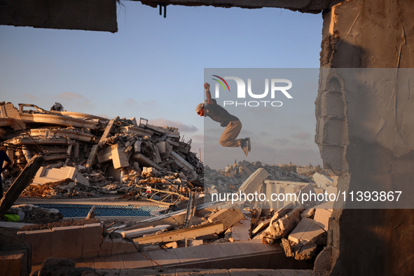 A Palestinian youth is practicing parkour at the ruins of a building destroyed in recent Israeli air strikes, in Zawayda in the central Gaza...