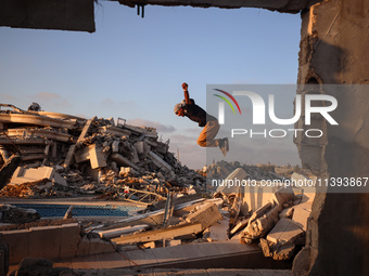 A Palestinian youth is practicing parkour at the ruins of a building destroyed in recent Israeli air strikes, in Zawayda in the central Gaza...