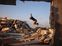 A Palestinian youth is practicing parkour at the ruins of a building destroyed in recent Israeli air strikes, in Zawayda in the central Gaza...