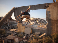 A Palestinian youth is practicing parkour at the ruins of a building destroyed in recent Israeli air strikes, in Zawayda in the central Gaza...