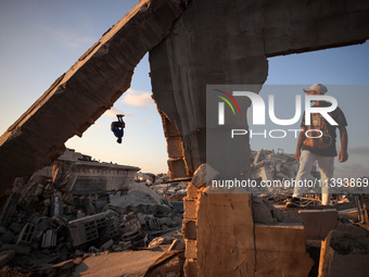 Palestinian youths are playing parkour at the ruins of a building destroyed in recent Israeli air strikes, in Zawayda, in the central Gaza S...