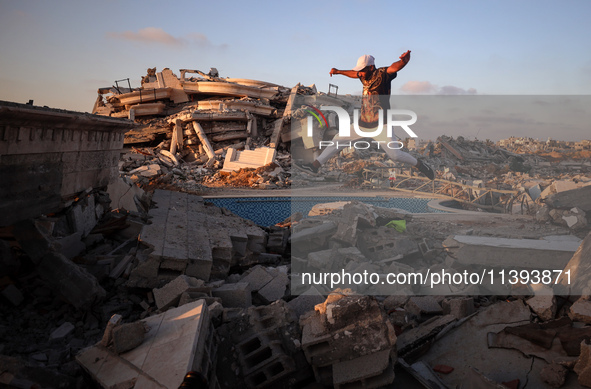 A Palestinian youth is practicing parkour at the ruins of a building destroyed in recent Israeli air strikes, in Zawayda in the central Gaza...