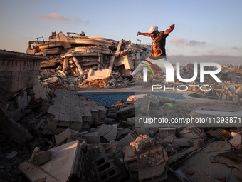 A Palestinian youth is practicing parkour at the ruins of a building destroyed in recent Israeli air strikes, in Zawayda in the central Gaza...