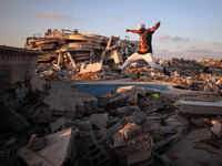 A Palestinian youth is practicing parkour at the ruins of a building destroyed in recent Israeli air strikes, in Zawayda in the central Gaza...