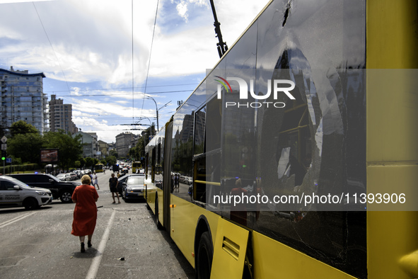 People are walking in a street covered with debris past a damaged trolleybus after a Russian missile strike in Kyiv, Ukraine, on July 08, 20...