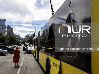 People are walking in a street covered with debris past a damaged trolleybus after a Russian missile strike in Kyiv, Ukraine, on July 08, 20...