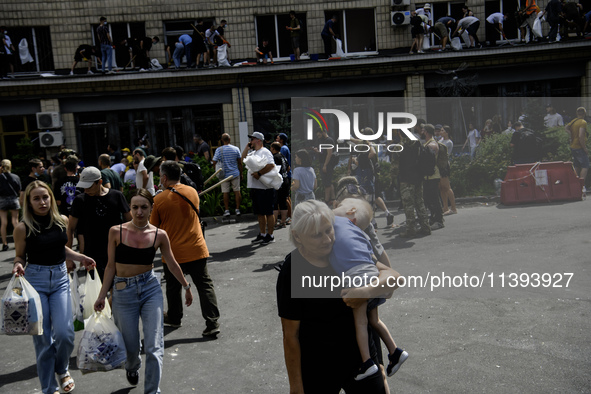 A woman is carrying a child in her arms while rescuers and volunteers are working at Ohmatdyt Children's Hospital, which was strongly damage...