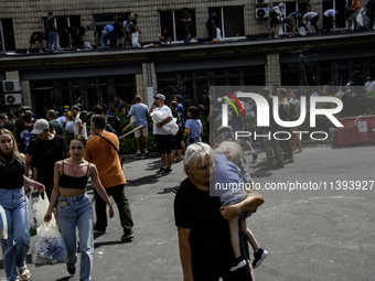 A woman is carrying a child in her arms while rescuers and volunteers are working at Ohmatdyt Children's Hospital, which was strongly damage...