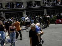 A woman is carrying a child in her arms while rescuers and volunteers are working at Ohmatdyt Children's Hospital, which was strongly damage...