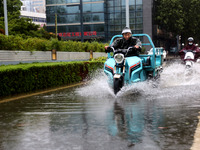 People are riding their bikes on a flooded road in Lianyun district, Lianyungang, China, on July 9, 2024. (