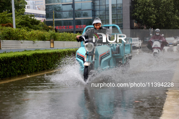 People are riding their bikes on a flooded road in Lianyun district, Lianyungang, China, on July 9, 2024. 