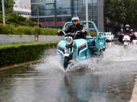 People are riding their bikes on a flooded road in Lianyun district, Lianyungang, China, on July 9, 2024. (