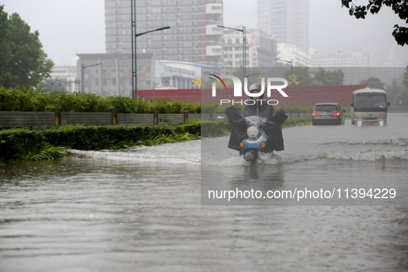 People are riding their bikes on a flooded road in Lianyun district, Lianyungang, China, on July 9, 2024. 