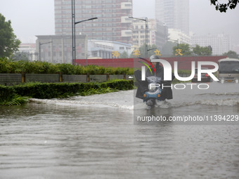 People are riding their bikes on a flooded road in Lianyun district, Lianyungang, China, on July 9, 2024. (