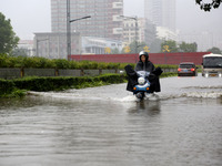 People are riding their bikes on a flooded road in Lianyun district, Lianyungang, China, on July 9, 2024. (