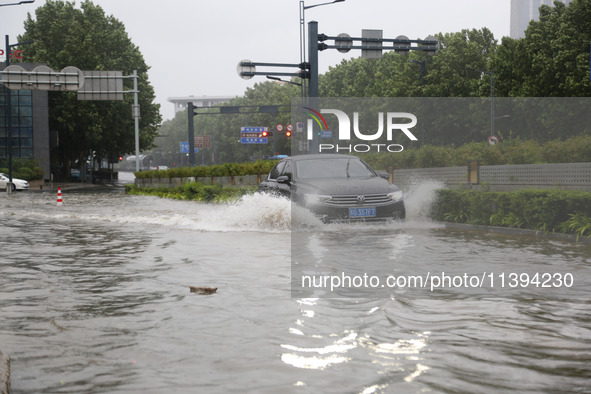 Vehicles are driving slowly through water on a road in Lianyun district, Lianyungang city, East China's Jiangsu province, on July 9, 2024. 