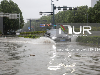 Vehicles are driving slowly through water on a road in Lianyun district, Lianyungang city, East China's Jiangsu province, on July 9, 2024. (