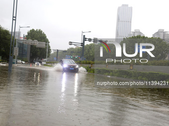 Vehicles are driving slowly through water on a road in Lianyun district, Lianyungang city, East China's Jiangsu province, on July 9, 2024. (