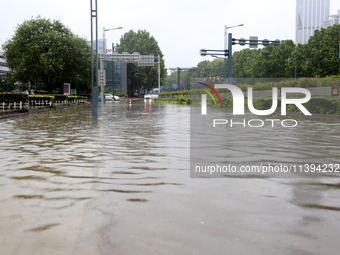 Vehicles are driving slowly through water on a road in Lianyun district, Lianyungang city, East China's Jiangsu province, on July 9, 2024. (