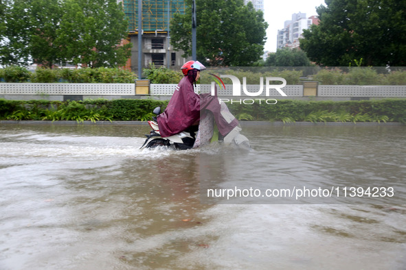 People are riding their bikes on a flooded road in Lianyun district, Lianyungang, China, on July 9, 2024. 