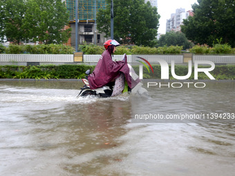 People are riding their bikes on a flooded road in Lianyun district, Lianyungang, China, on July 9, 2024. (