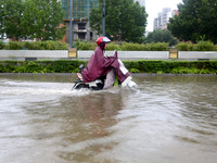 People are riding their bikes on a flooded road in Lianyun district, Lianyungang, China, on July 9, 2024. (