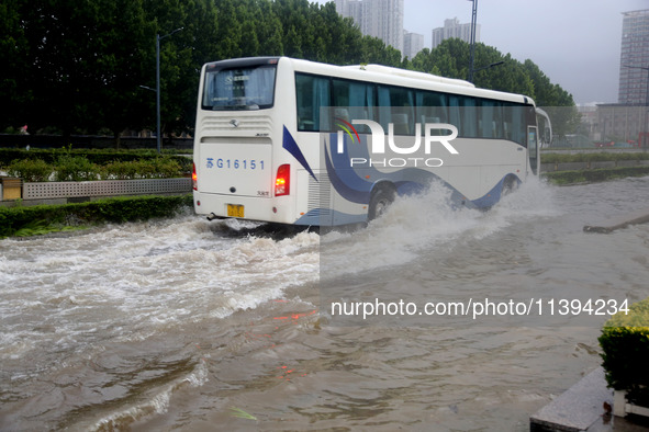 Vehicles are driving slowly through water on a road in Lianyun district, Lianyungang city, East China's Jiangsu province, on July 9, 2024. 