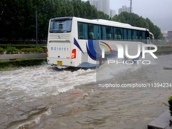 Vehicles are driving slowly through water on a road in Lianyun district, Lianyungang city, East China's Jiangsu province, on July 9, 2024. (