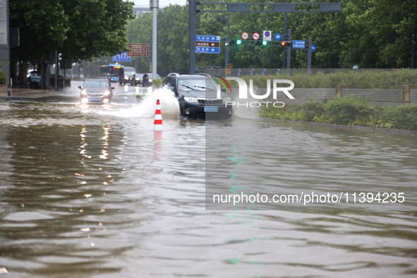 Vehicles are driving slowly through water on a road in Lianyun district, Lianyungang city, East China's Jiangsu province, on July 9, 2024. 