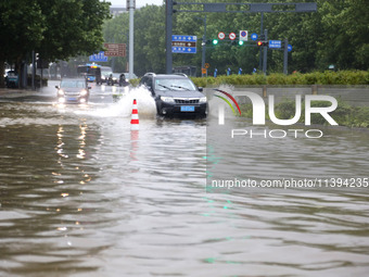 Vehicles are driving slowly through water on a road in Lianyun district, Lianyungang city, East China's Jiangsu province, on July 9, 2024. (