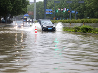 Vehicles are driving slowly through water on a road in Lianyun district, Lianyungang city, East China's Jiangsu province, on July 9, 2024. (