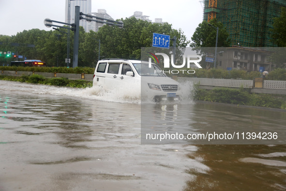 Vehicles are driving slowly through water on a road in Lianyun district, Lianyungang city, East China's Jiangsu province, on July 9, 2024. 