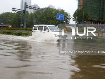 Vehicles are driving slowly through water on a road in Lianyun district, Lianyungang city, East China's Jiangsu province, on July 9, 2024. (