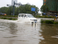 Vehicles are driving slowly through water on a road in Lianyun district, Lianyungang city, East China's Jiangsu province, on July 9, 2024. (