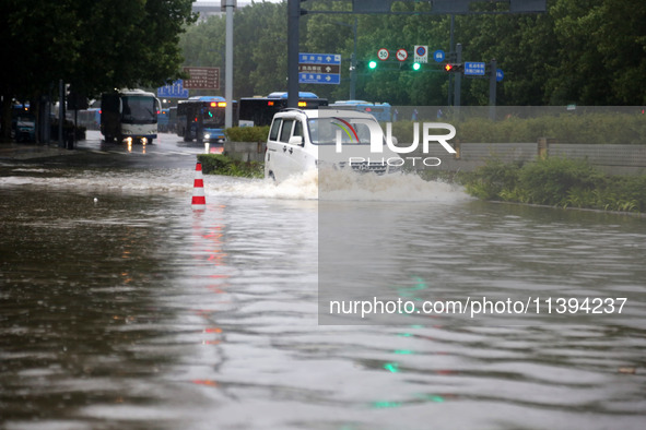 Vehicles are driving slowly through water on a road in Lianyun district, Lianyungang city, East China's Jiangsu province, on July 9, 2024. 