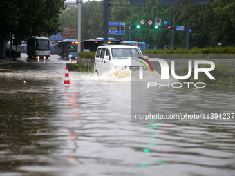 Vehicles are driving slowly through water on a road in Lianyun district, Lianyungang city, East China's Jiangsu province, on July 9, 2024. (