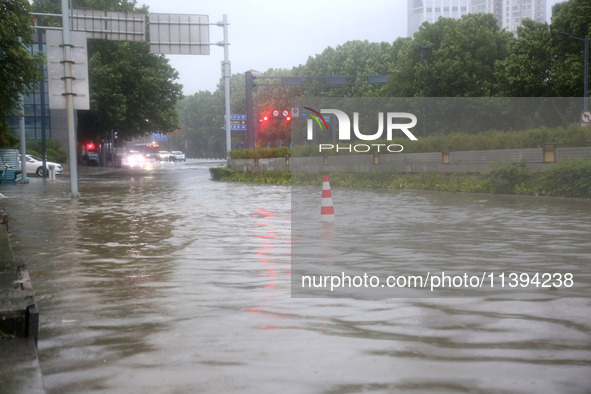 Vehicles are driving slowly through water on a road in Lianyun district, Lianyungang city, East China's Jiangsu province, on July 9, 2024. 