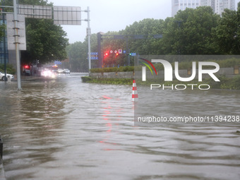 Vehicles are driving slowly through water on a road in Lianyun district, Lianyungang city, East China's Jiangsu province, on July 9, 2024. (