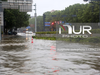 Vehicles are driving slowly through water on a road in Lianyun district, Lianyungang city, East China's Jiangsu province, on July 9, 2024. (