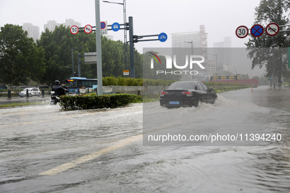 Vehicles are driving slowly through water on a road in Lianyun district, Lianyungang city, East China's Jiangsu province, on July 9, 2024. 