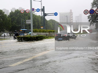 Vehicles are driving slowly through water on a road in Lianyun district, Lianyungang city, East China's Jiangsu province, on July 9, 2024. (