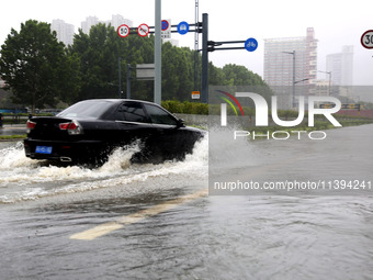 Vehicles are driving slowly through water on a road in Lianyun district, Lianyungang city, East China's Jiangsu province, on July 9, 2024. (