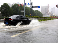 Vehicles are driving slowly through water on a road in Lianyun district, Lianyungang city, East China's Jiangsu province, on July 9, 2024. (