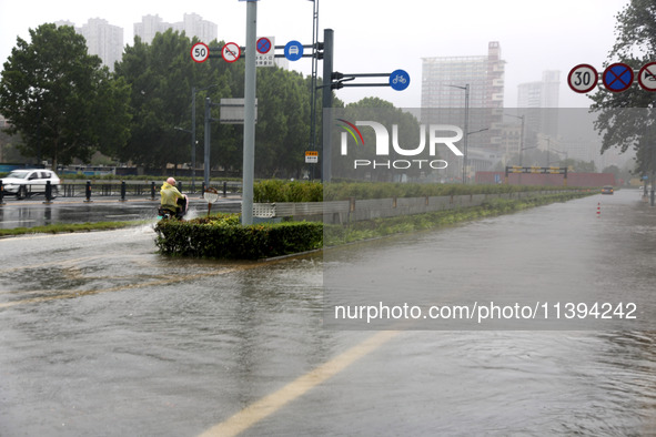 People are riding their bikes on a flooded road in Lianyun district, Lianyungang, China, on July 9, 2024. 