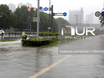 People are riding their bikes on a flooded road in Lianyun district, Lianyungang, China, on July 9, 2024. (