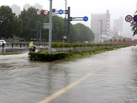 People are riding their bikes on a flooded road in Lianyun district, Lianyungang, China, on July 9, 2024. (