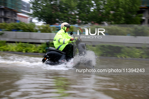 People are riding their bikes on a flooded road in Lianyun district, Lianyungang, China, on July 9, 2024. 